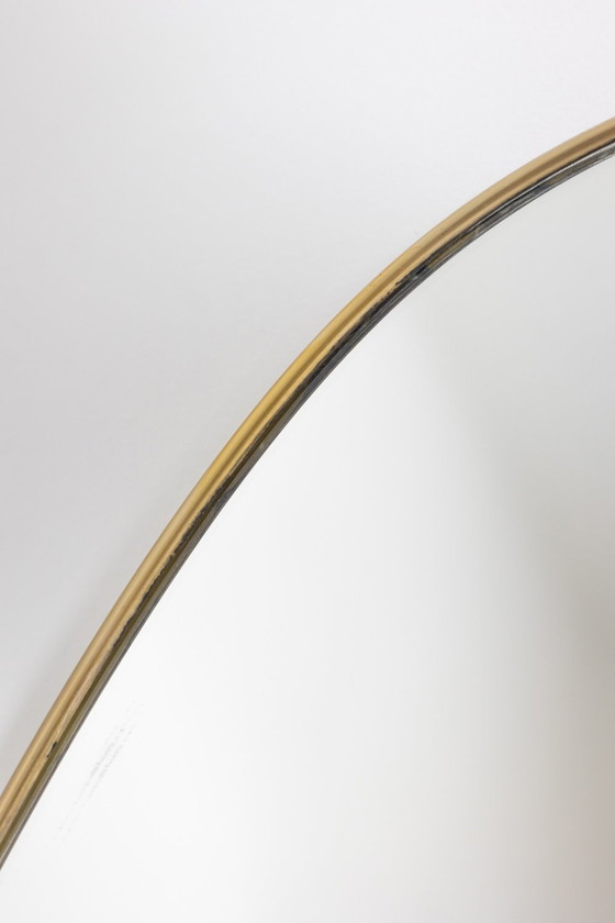 Image 1 of Oval-shaped mirror set with a gilded brass rod. Circa 1970.