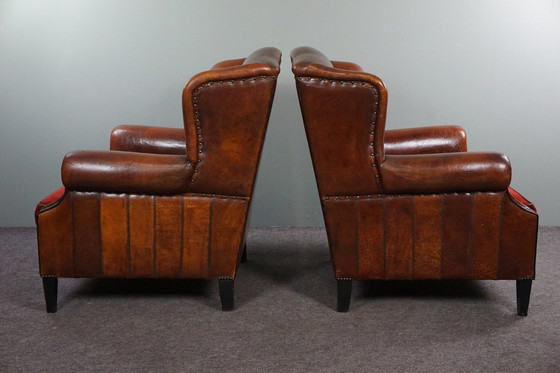 Image 1 of Ensemble de deux chaises à oreilles en cuir de mouton avec coussins d'assise en velours rouge