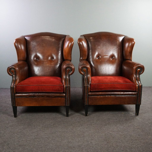 Ensemble de deux chaises à oreilles en cuir de mouton avec coussins d'assise en velours rouge