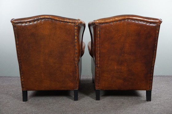 Image 1 of Ensemble de deux chaises à oreilles en cuir de mouton avec coussins d'assise en velours rouge