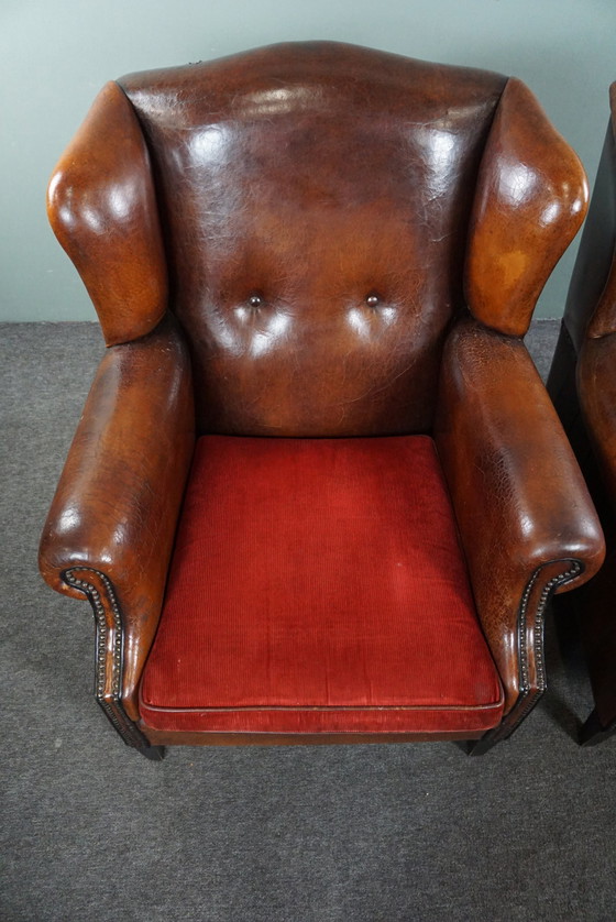 Image 1 of Ensemble de deux chaises à oreilles en cuir de mouton avec coussins d'assise en velours rouge