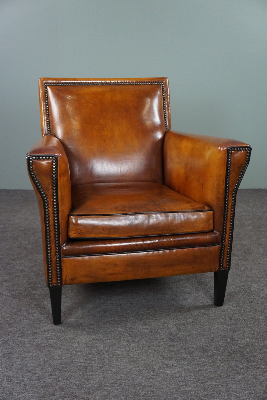 Sillón Art Déco con ribetes negros y clavos decorativos.