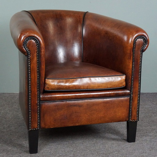 Fauteuil club en peau de mouton avec passepoil noir et rivets décoratifs