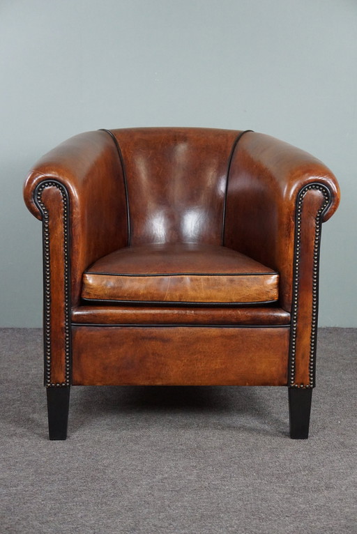 Fauteuil club en peau de mouton avec passepoil noir et rivets décoratifs