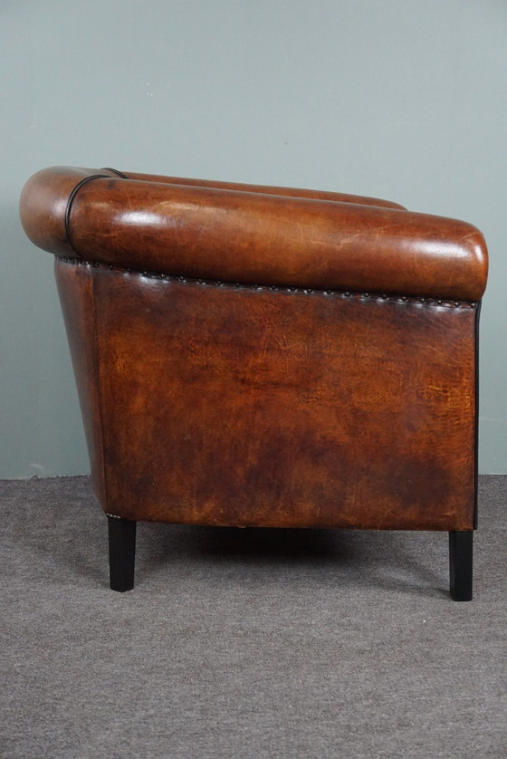 Image 1 of Fauteuil club en peau de mouton avec passepoil noir et rivets décoratifs