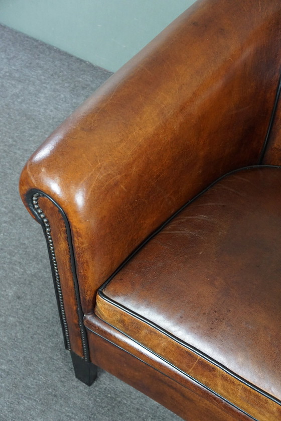 Image 1 of Fauteuil club en peau de mouton avec passepoil noir et rivets décoratifs