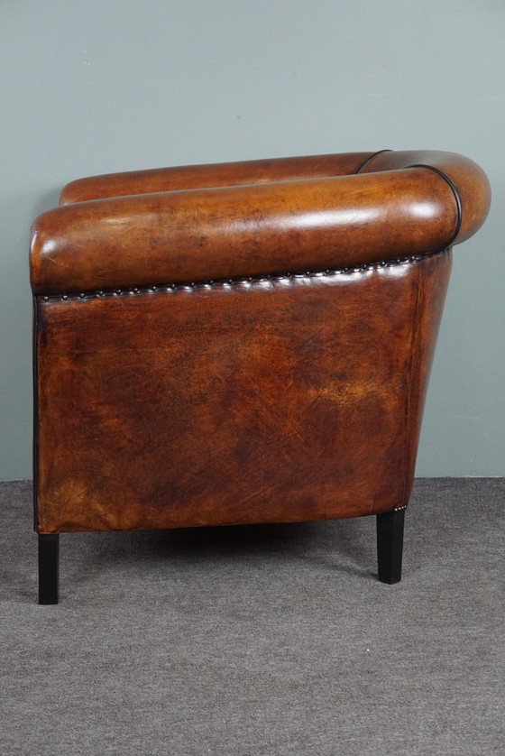 Image 1 of Fauteuil club en peau de mouton avec passepoil noir et rivets décoratifs