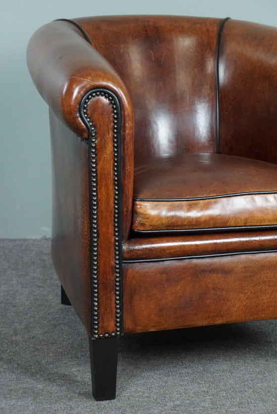 Image 1 of Fauteuil club en peau de mouton avec passepoil noir et rivets décoratifs