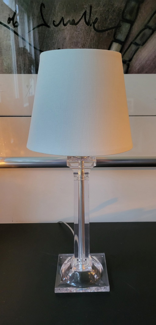 Lampe de table moderne en plexiglas transparent avec abat-jour blanc.