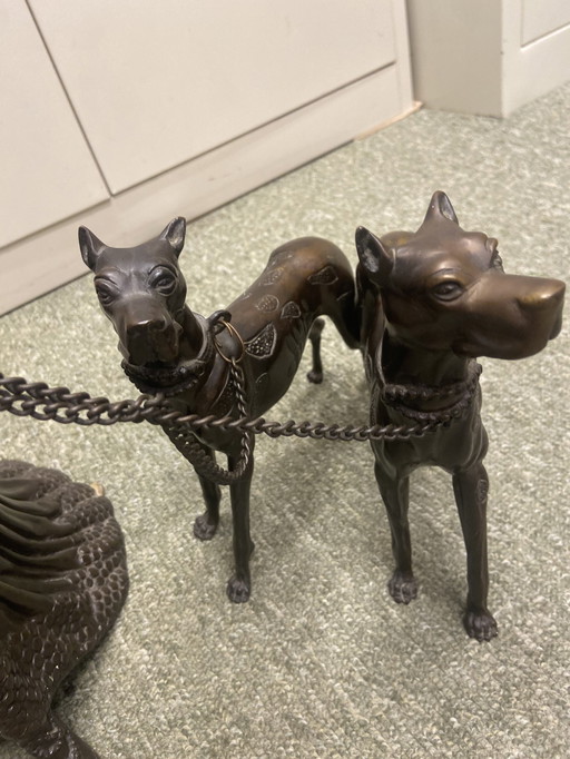 Statue en métal d'une femme avec deux chiens en laisse