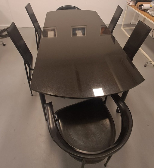 Fasem Une table à manger en pierre, deux fauteuils en cuir noir, quatre chaises hautes en cuir noir